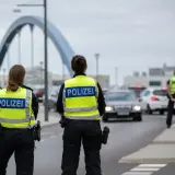 Policjanci w kamizelkach z napisem POLIZEI prowadzą kontrole na granicy niemieckiej. Ruch samochodowy jest spowolniony.