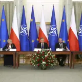 Spotkanie przy stole z flagami Polski, UE i NATO. Dyskusja o bezpieczeństwie i artykuł 5 NATO.