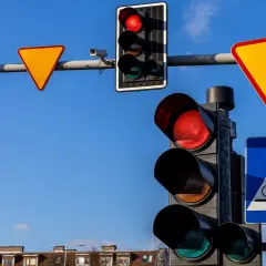 Sygnalizacja świetlna z czerwonym światłem, znaki drogowe: ustąp pierwszeństwa, przejście dla pieszych i rowerzystów.