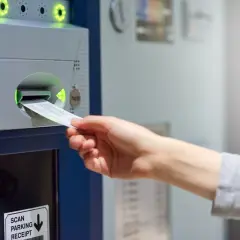 Ręka wkłada paragon do parkometru. Czy to europark mandat czy płacić?