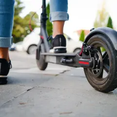 Osoba na hulajnodze elektrycznej jedzie po chodniku, zastanawiając się, czy hulajnogą elektryczną można jeździć po chodniku.