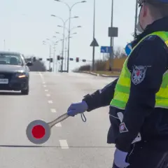 Policjant kieruje ruchem, egzekwując przepisy ruchu drogowego. Na drodze stoi samochód.