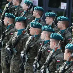 Żołnierze w zielonych beretach i mundurach stoją na baczność z karabinami. Zastanawiasz się, ile zarabia kapral w wojsku?
