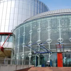 Nowoczesny budynek z przeszklonym wejściem i metalową fasadą. Tu zapadają ważne decyzje, tworząc precedens dla przyszłych pokoleń.