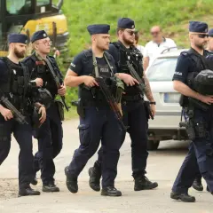 Grupa policjantów w pełnym rynsztunku, z bronią, maszeruje. To szkolenie policyjne, które przygotowuje ich do trudnych zadań.
