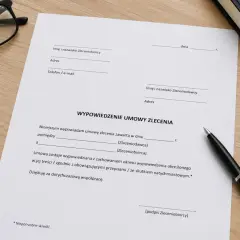 Dokument "Wypowiedzenie umowy zlecenia" leży na biurku obok okularów i długopisu.