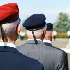 Trzech mężczyzn w garniturach i beretach, jeden z nich to kombatant, stoi w szeregu.