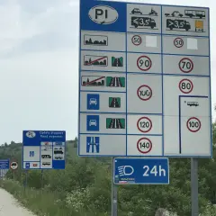 Znaki drogowe informują o opłatach i limitach prędkości na drodze ekspresowej. Maksymalna dozwolona prędkość dla samochodów osobowych to 140 km/h.
