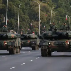 Parada wojskowa z nowoczesnym uzbrojeniem. Czołgi Leopard 2 maszerują ulicą, żołnierze pozdrawiają.