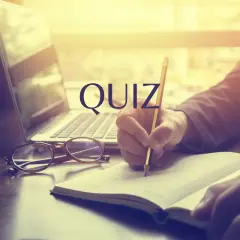 Quiz o prawach pracownika. Osoba pisze w notatniku przy laptopie i okularach.