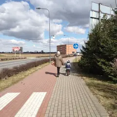 Kobieta z dzieckiem na rowerze idzie chodnikiem. Długość kolumny pieszych nie może przekraczać, ale tu jest tylko dwójka.