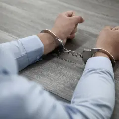 Ręce w kajdankach, być może schwytany członek gangu.