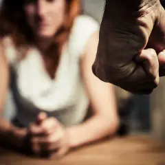 Zaciśnięta pięść grozi kobiecie, która siedzi z opuszczoną głową. To obraz szantażu i przemocy.