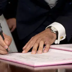 Mężczyzna w garniturze podpisuje dokument. Na nadgarstku ma zegarek, a przy nim spinki do mankietów. To ważny moment, być może związany z 231 kk.