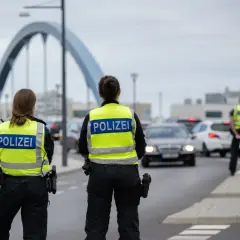Policjanci w kamizelkach z napisem POLIZEI prowadzą kontrole na granicy niemieckiej. Ruch samochodowy jest spowolniony.