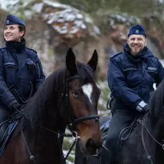 Policjanci na koniach, w tym przełożony, patrolują zimowy teren.