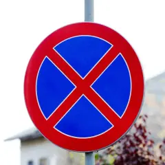 Znak drogowy: zakaz zatrzymywania. Czerwone koło z niebieskim tłem i dwoma czerwonymi skrzyżowanymi pasami.