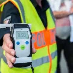 Policjant pokazuje alkomat z wynikiem 0.93 promila. To przypomnienie o **limicie alkoholu w Polsce** i odpowiedzialności za kierownicą.