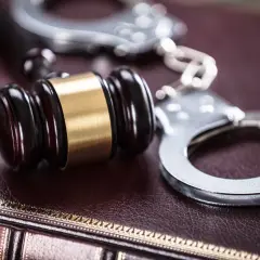 Młotek sędziowski i kajdanki na księdze. Czy można wycofać zeznania na policji? To pytanie nurtuje wielu.
