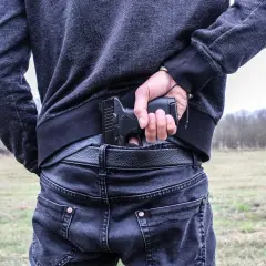 Mężczyzna chowa pistolet za pasem, gotowy do egzekwowania haraczu.