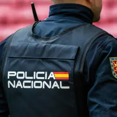 Policjant w kamizelce z napisem "POLICIA NACIONAL" i flagą Hiszpanii. Służba w policji Hiszpanii to odpowiedzialność.
