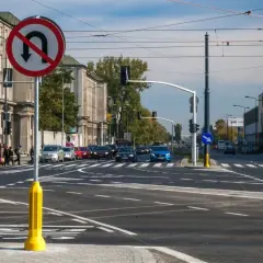 Znak zakazu skrętu w lewo na skrzyżowaniu z ruchem ulicznym i pieszymi.