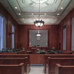 Pusta sala sądowa, gotowa na złożenie **zażalenia**. Drewniane ławy i podwyższenie dla sędziego tworzą uroczystą atmosferę.