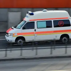 Ambulans z niebieskimi sygnałami świetlnymi, jadący na kursie pojazdy uprzywilejowane.
