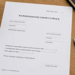 Dokument wypowiedzenia umowy o pracę, zgodnie z art. 30 par. 1 pkt 2 Kodeksu pracy, leży na drewnianym biurku obok długopisu.