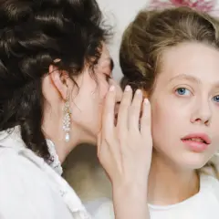Szeptane plotki, które mogą prowadzić do zniesławienia, rozchodzą się między dwiema kobietami w stylizacjach retro.