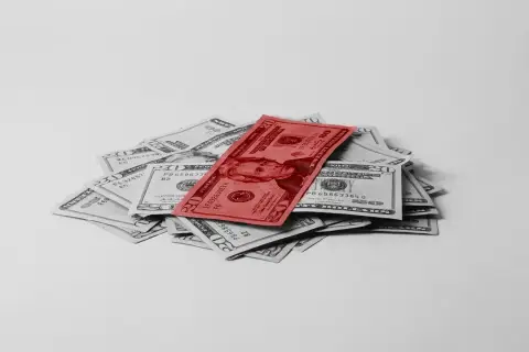 Stos dwudziestodolarowych banknotów, z jednym czerwonym na wierzchu, symbolizuje fundusz gwarantowanych świadczeń pracowniczych.