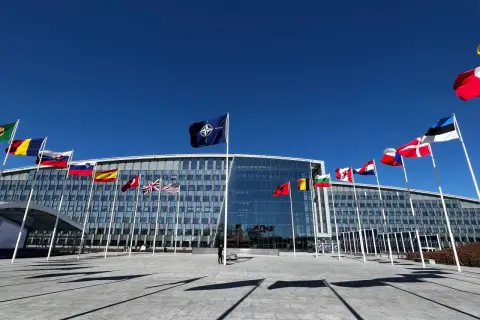 Przed budynkiem NATO, symbolizującym art. 5 traktatu, powiewają flagi państw członkowskich.
