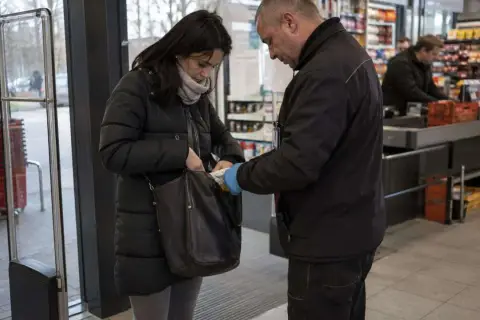 Ochroniarz w sklepie sprawdza zawartość torby kobiety. W tle widać kasy i półki z produktami. Numer 278 kk.