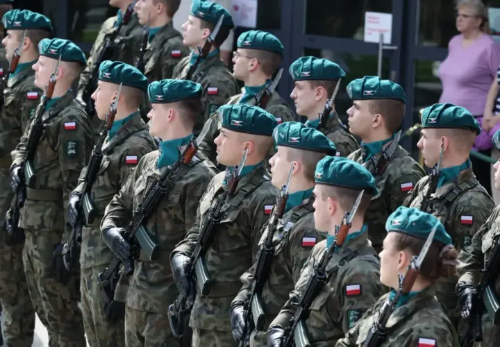 Żołnierze w zielonych beretach i mundurach stoją na baczność z karabinami. Zastanawiasz się, ile zarabia kapral w wojsku?