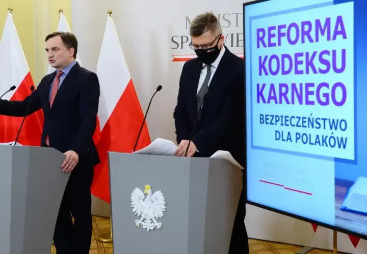 Konferencja prasowa dotycząca reformy kodeksu karnego. Mówcy przy mównicach z godłem Polski, na ekranie hasło "Bezpieczeństwo dla Polaków" i symbole sprawiedliwości.