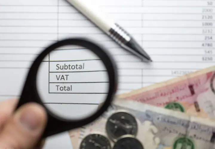 Pod lupą widać napisy "Subtotal", "VAT", "Total" na tle dokumentu z cyframi. Obok leżą banknoty i monety, co sugeruje analizę finansową zgodną z art. 96 ust. 9a pkt 2.
