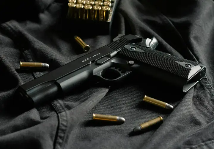 Czarny pistolet GSG-1911 i amunicja na ciemnym tle. Idealny do strzelectwa sportowego.