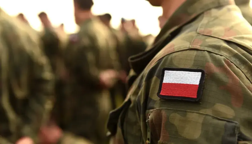 Żołnierz w mundurze polowym z naszywką flagi Polski. Weteran dumny ze swojej służby.