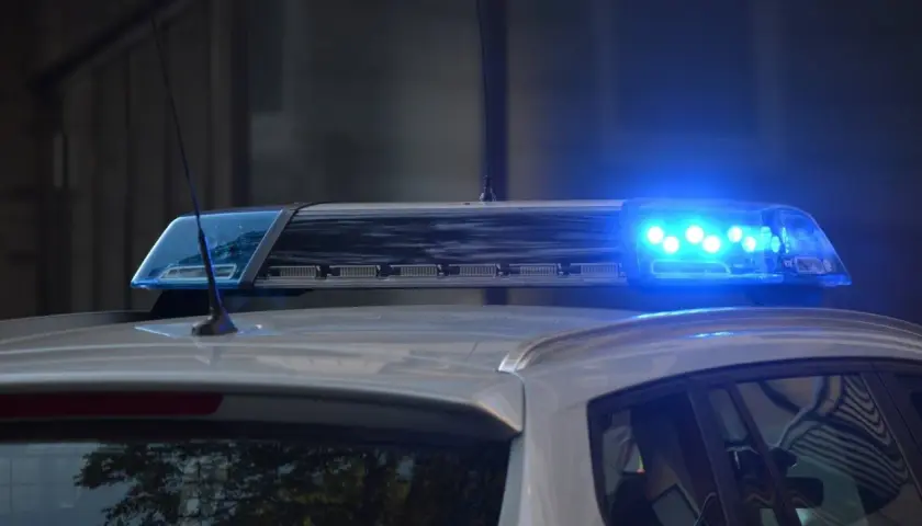 Niebieskie światła pojazdu uprzywilejowanego migają na dachu radiowozu.