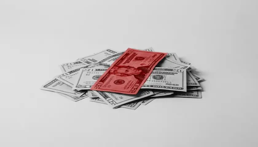 Stos dwudziestodolarowych banknotów, z jednym czerwonym na wierzchu, symbolizuje fundusz gwarantowanych świadczeń pracowniczych.