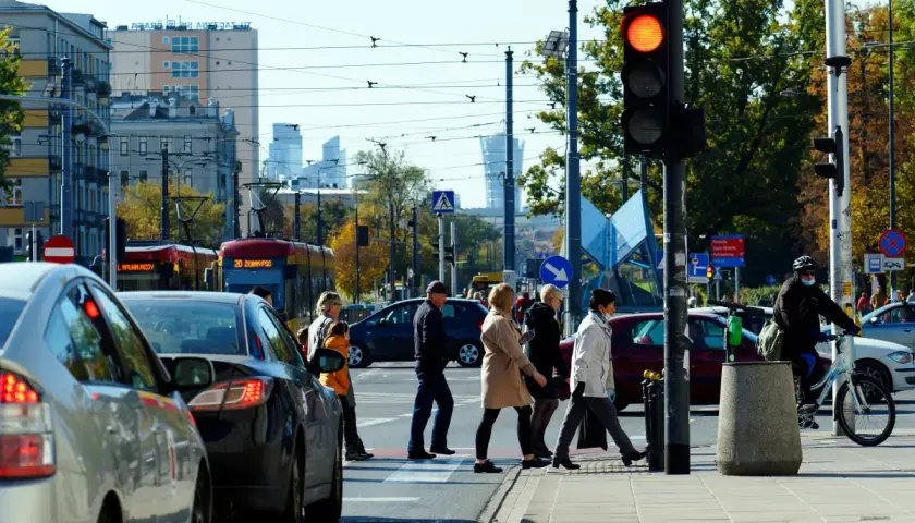 Ludzie przechodzą przez pasy, sygnalizacja świetlna czerwona. Nowe przepisy drogowe 2026 wkrótce, ale dziś ostrożność na ulicy kluczowa.