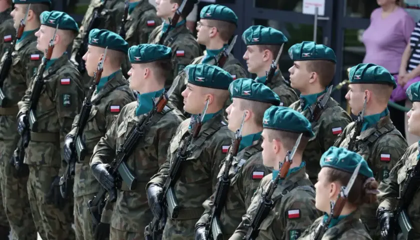 Żołnierze w zielonych beretach i mundurach stoją na baczność z karabinami. Zastanawiasz się, ile zarabia kapral w wojsku?