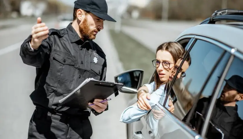 Policjant spisuje dane kierowcy. Zastanawia się, ile lat do policji potrzeba, by móc taką kontrolę przeprowadzać.