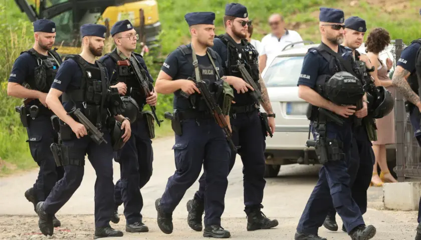 Grupa policjantów w pełnym rynsztunku, z bronią, maszeruje. To szkolenie policyjne, które przygotowuje ich do trudnych zadań.
