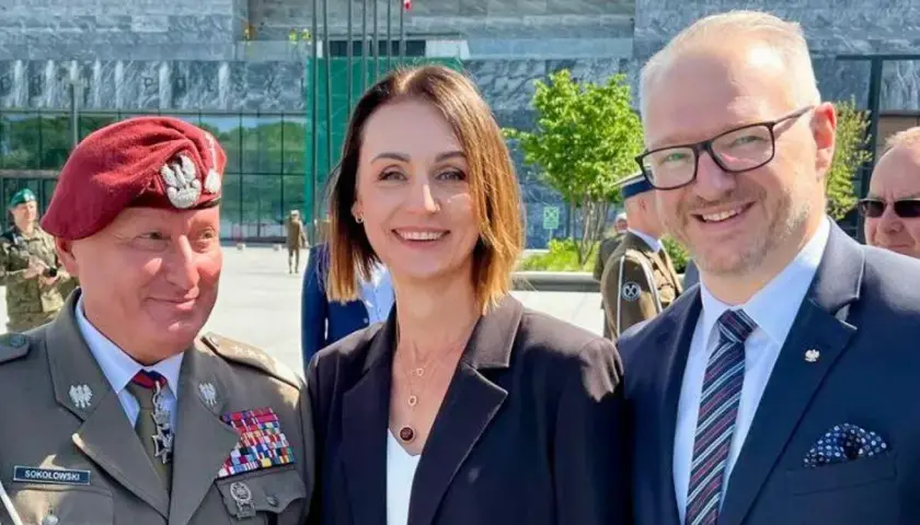 Dowódca generalny rodzajów sił zbrojnych w towarzystwie kobiety i mężczyzny w garniturze, na tle nowoczesnego budynku.