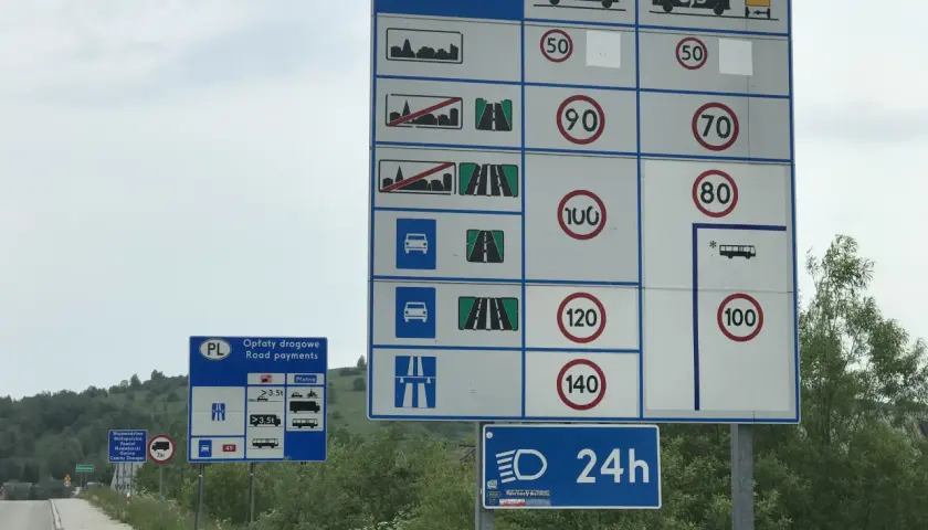 Znaki drogowe informują o opłatach i limitach prędkości na drodze ekspresowej. Maksymalna dozwolona prędkość dla samochodów osobowych to 140 km/h.