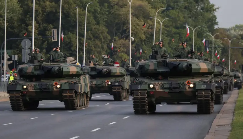 Parada wojskowa z nowoczesnym uzbrojeniem. Czołgi Leopard 2 maszerują ulicą, żołnierze pozdrawiają.