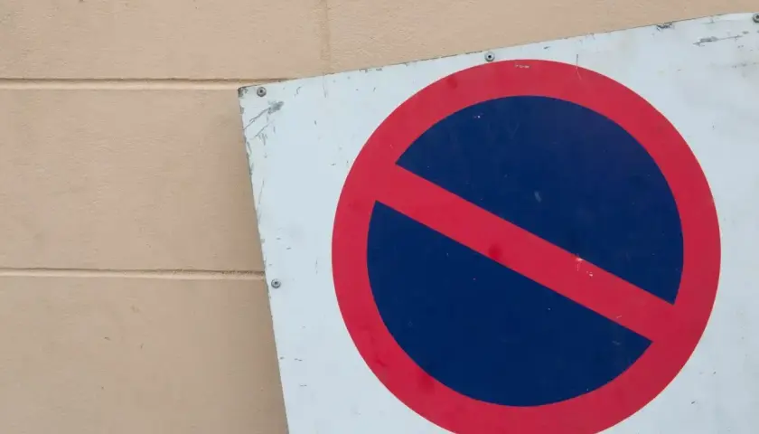 Znak b35 zakazu zatrzymywania się. Czerwone koło z czerwoną przekątną na niebieskim tle.