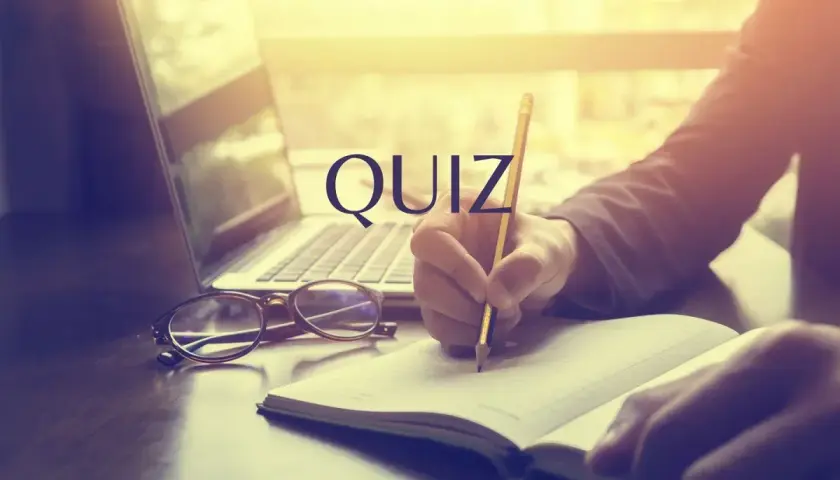 Quiz o prawach pracownika. Osoba pisze w notatniku przy laptopie i okularach.