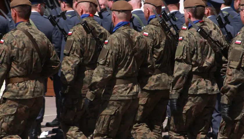 Żołnierze w mundurach polowych, z karabinami, maszerują w szyku. Widać polskie flagi na rękawach. To wyższy stopień podoficerski w marynarce wojennej.